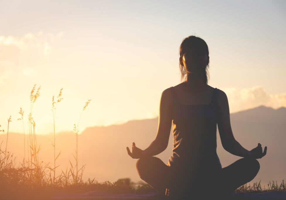 silhouette fitness girl practicing yoga on mountain with sun light