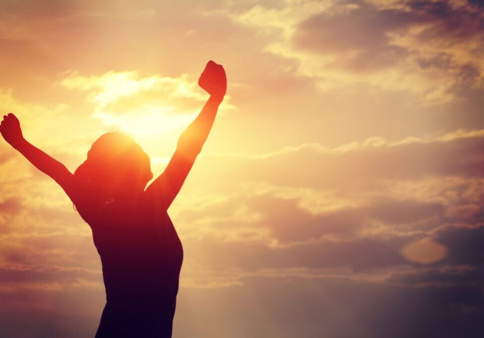 cheering woman open arms at sunrise seaside